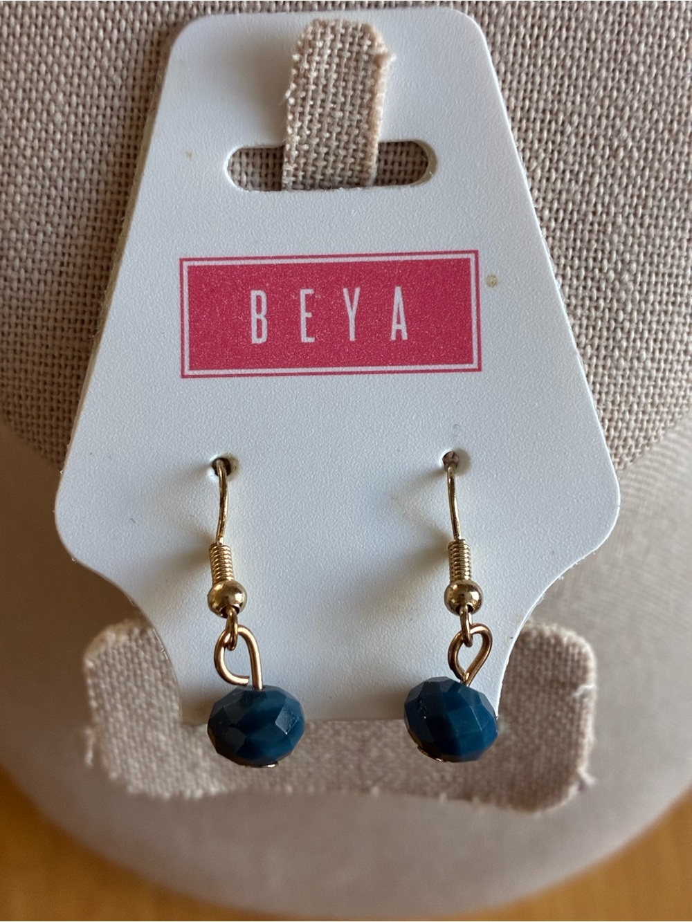 These are BEYA brand dangle earrings featuring faceted teal beads.